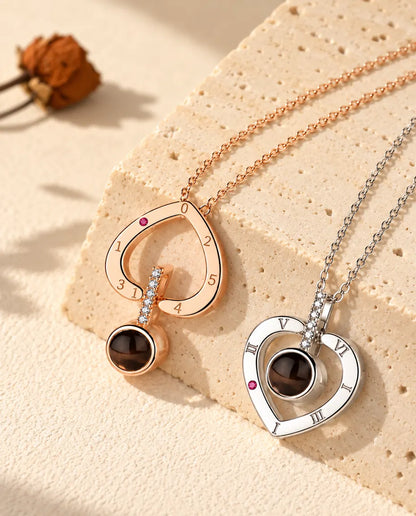 Corazón de números romanos en color oro rosa llevado del revés, junto al de plata llevado de la forma habitual