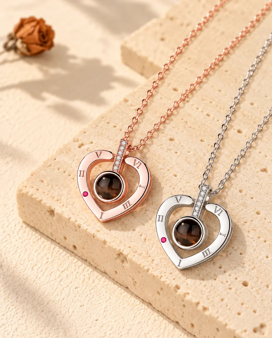 Collares de corazón con números romanos en color oro rosa y en plata, colocados en diagonal sobre yeso