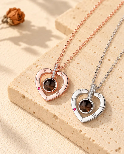 Collares de corazón con números romanos en color oro rosa y en plata, colocados en diagonal sobre yeso