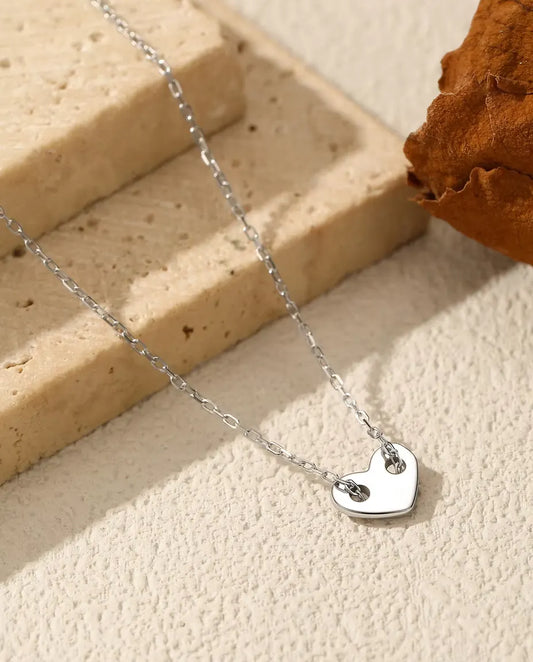 Collar con Corazón en Plata 925 - colgante sobre una superficie clara junto a una losa de travertino