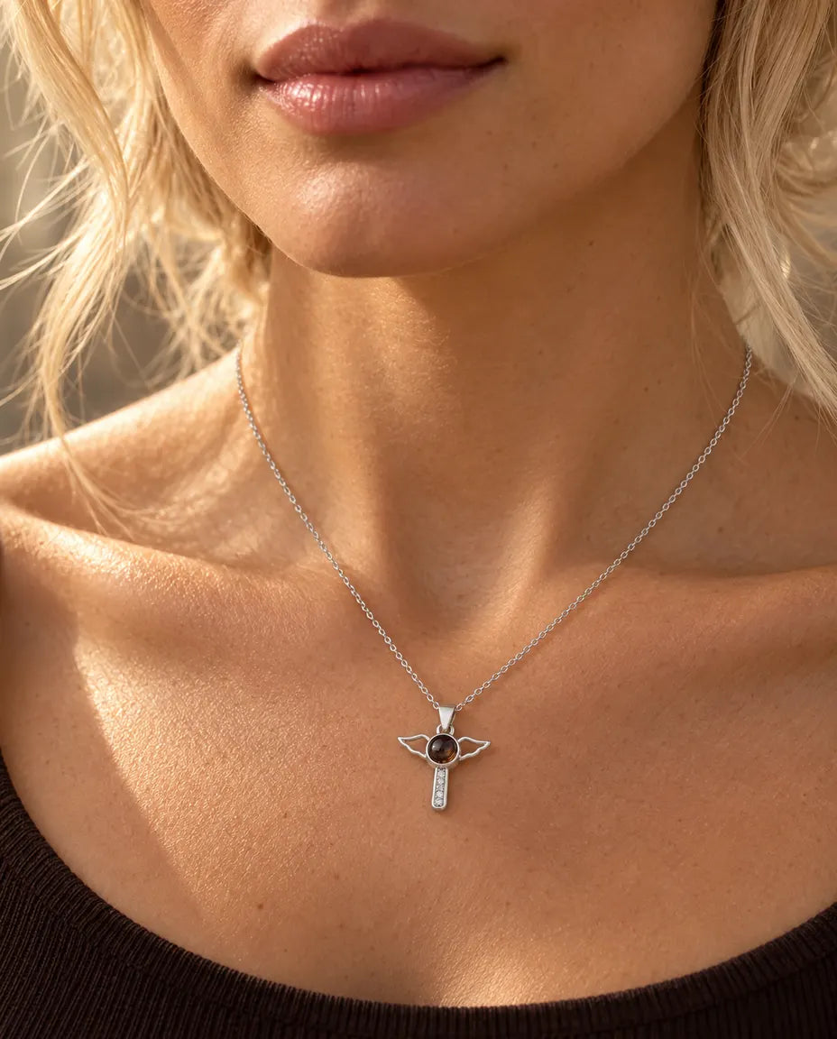 Mujer con un top marrón que lleva el collar de cruz con alas de ángel plateado