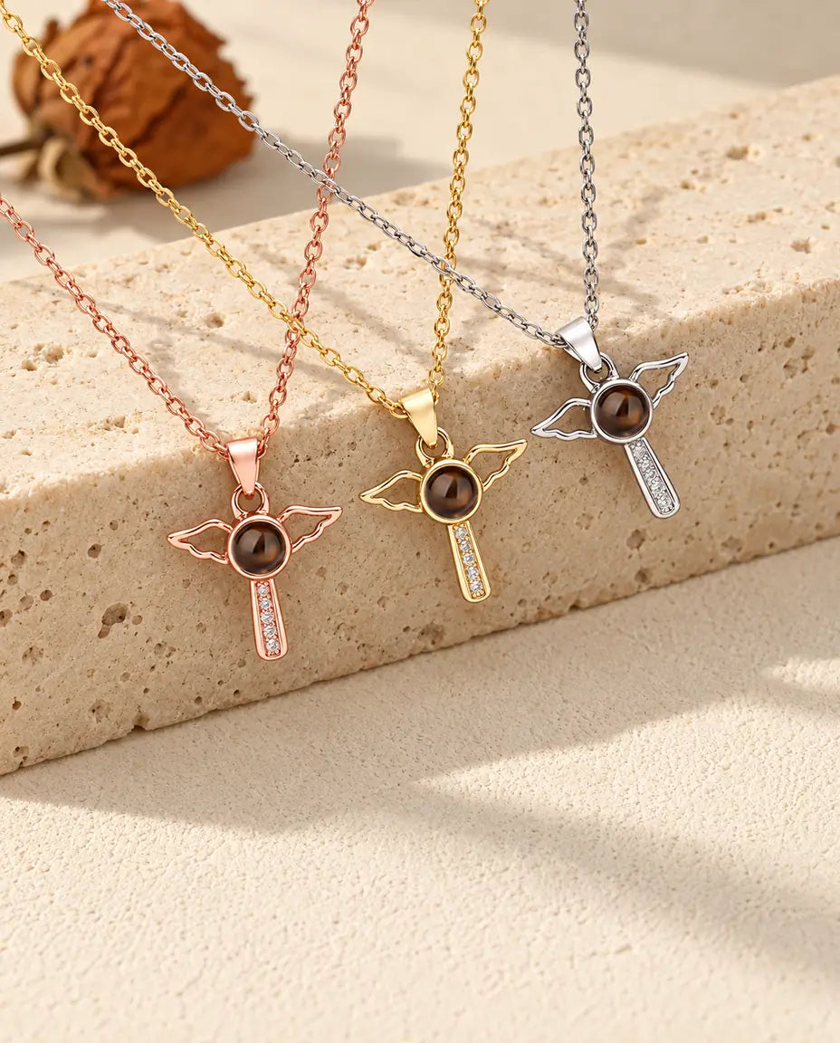 Collares de cruz con alas de ángel en plateado, dorado y color oro rosa sobre travertino