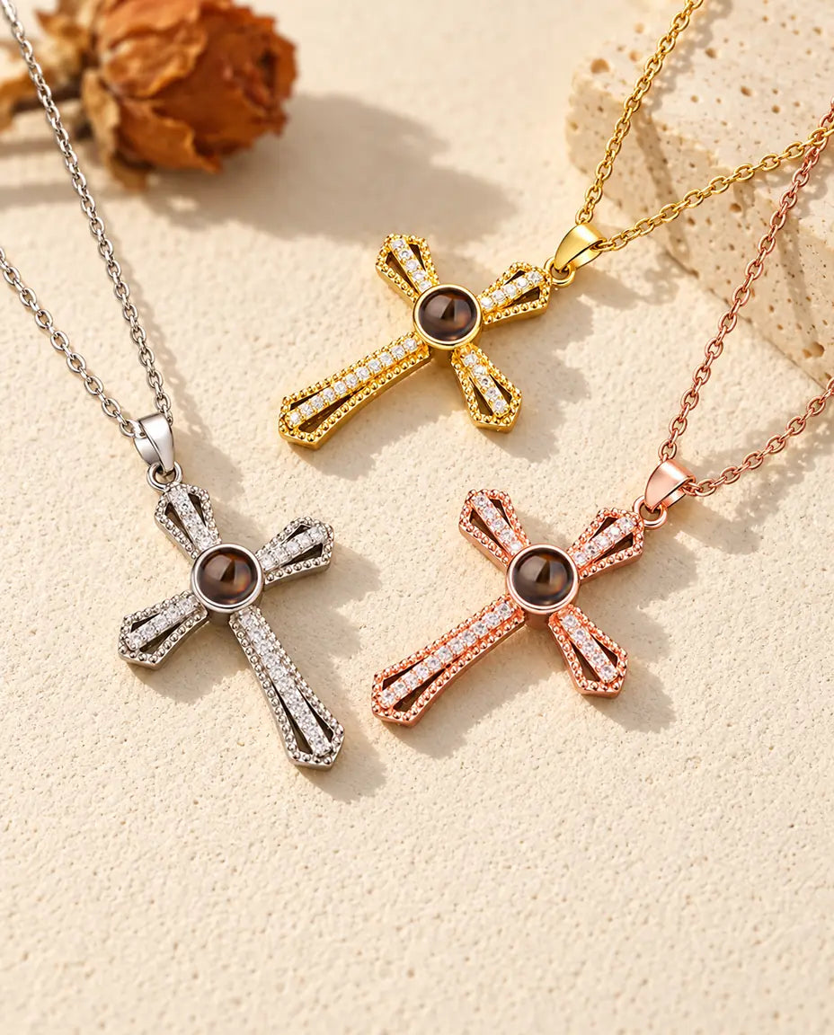 Collares cruz plateado, dorado y color oro rosa con bolas marrones de proyección, junto a una losa de travertino