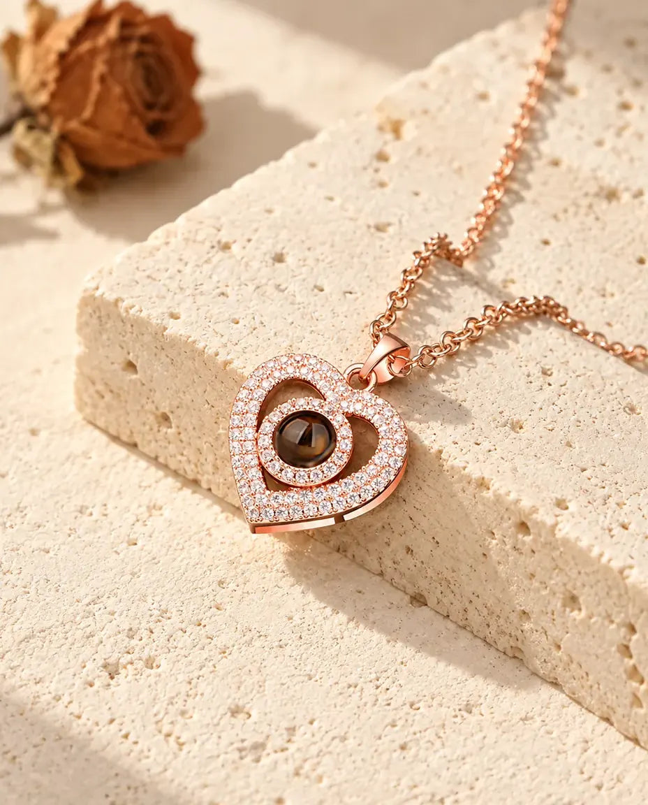 Colgante color oro rosa de doble corazón con circonitas, apoyado en un bloque de travertino
