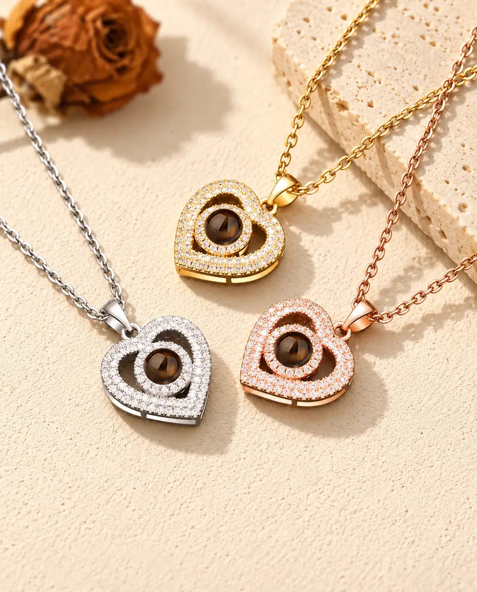 Collares de doble corazón en dorado, plateado y color oro rosa, junto a una losa de travertino