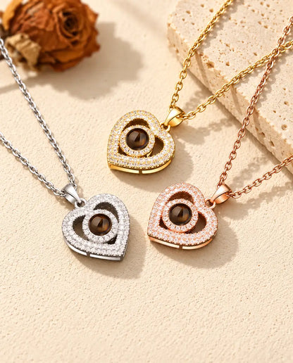 Collares de doble corazón en dorado, plateado y color oro rosa, junto a una losa de travertino