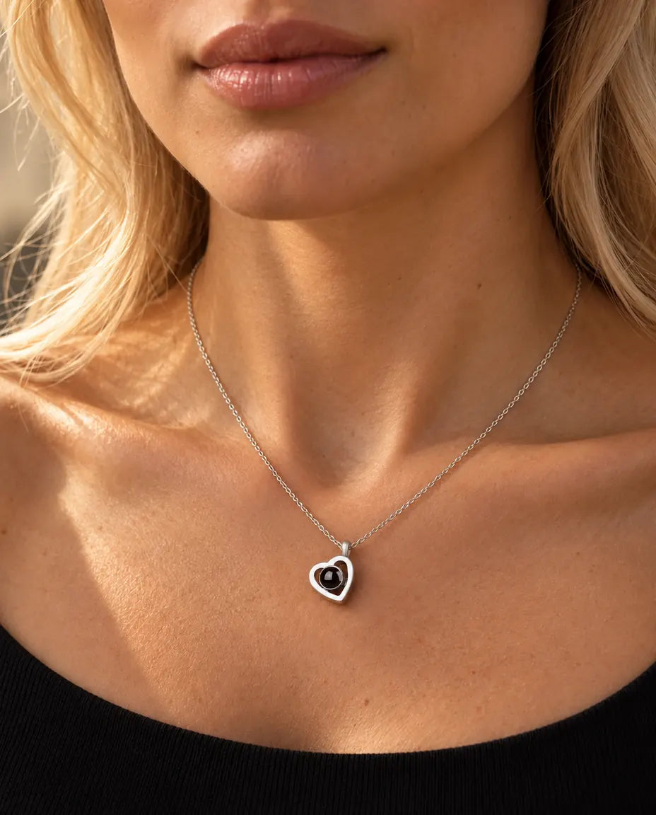 Mujer con un top negro de punto que lleva el pequeño collar de doble corazón de plata con foto dentro