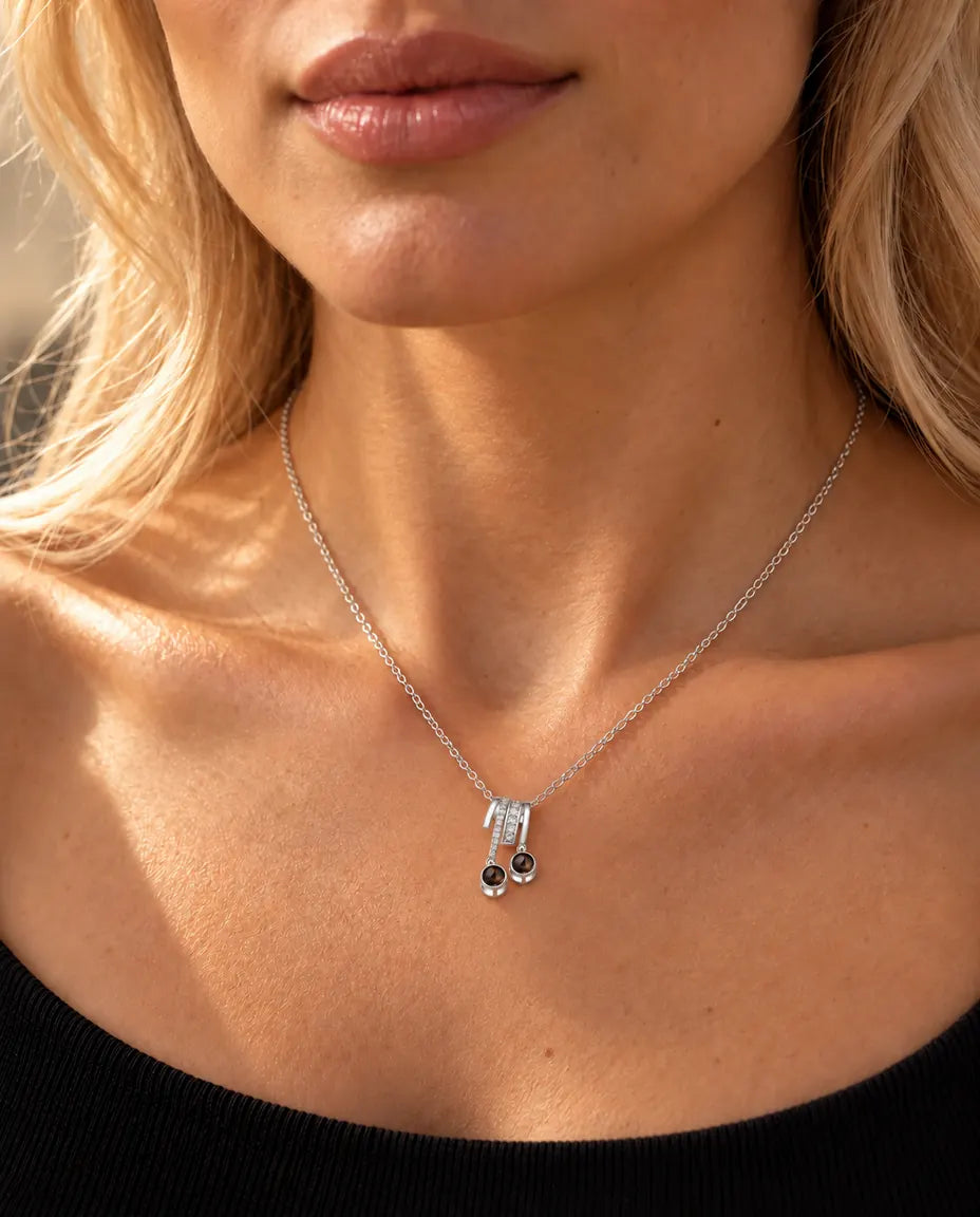 Mujer con un top negro de punto luciendo el collar plateado de dos bolas con foto dentro