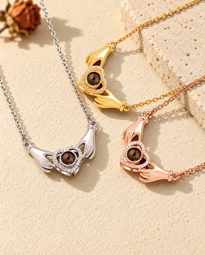 Collares de manos y corazón en plateado, dorado y color oro rosa, dispuestos sobre yeso y travertino
