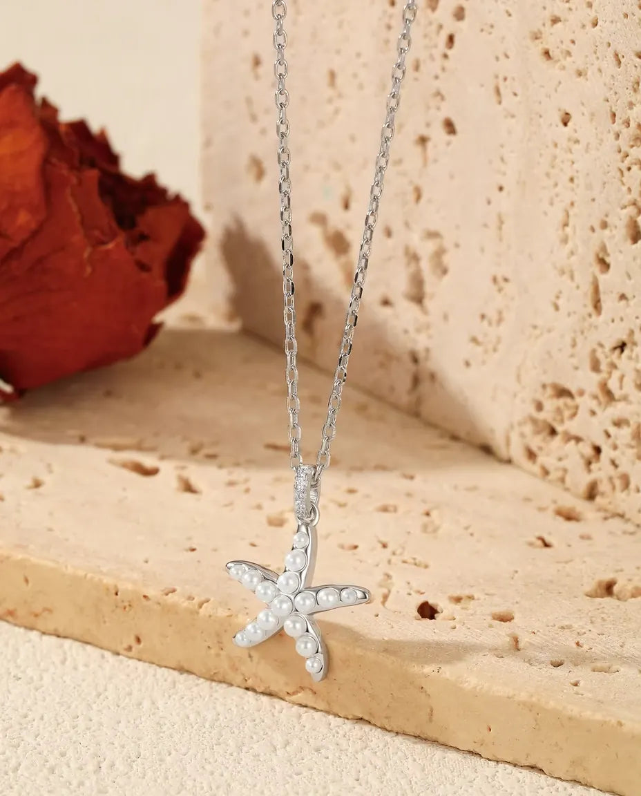 Collar Estrella de Mar en Plata 925 - colgante sobre el borde de una losa de travertino