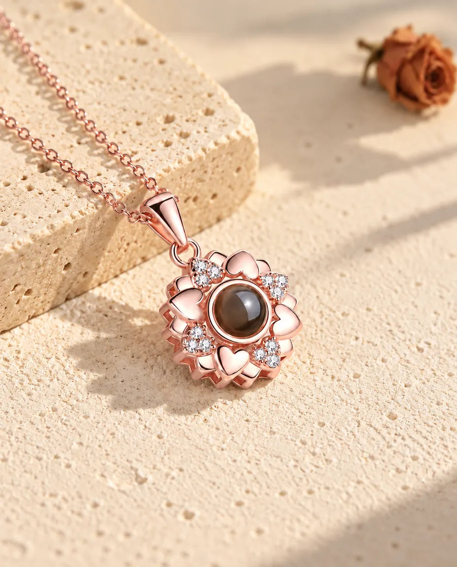 Collar de flor de corazones en color oro rosa tumbado sobre yeso, con luz cálida de sol