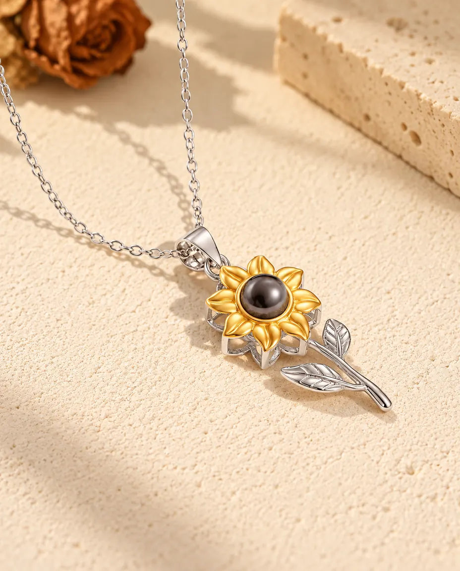Collar con foto dentro de girasol en plata de ley 925 con pétalos dorados, sobre yeso color crema
