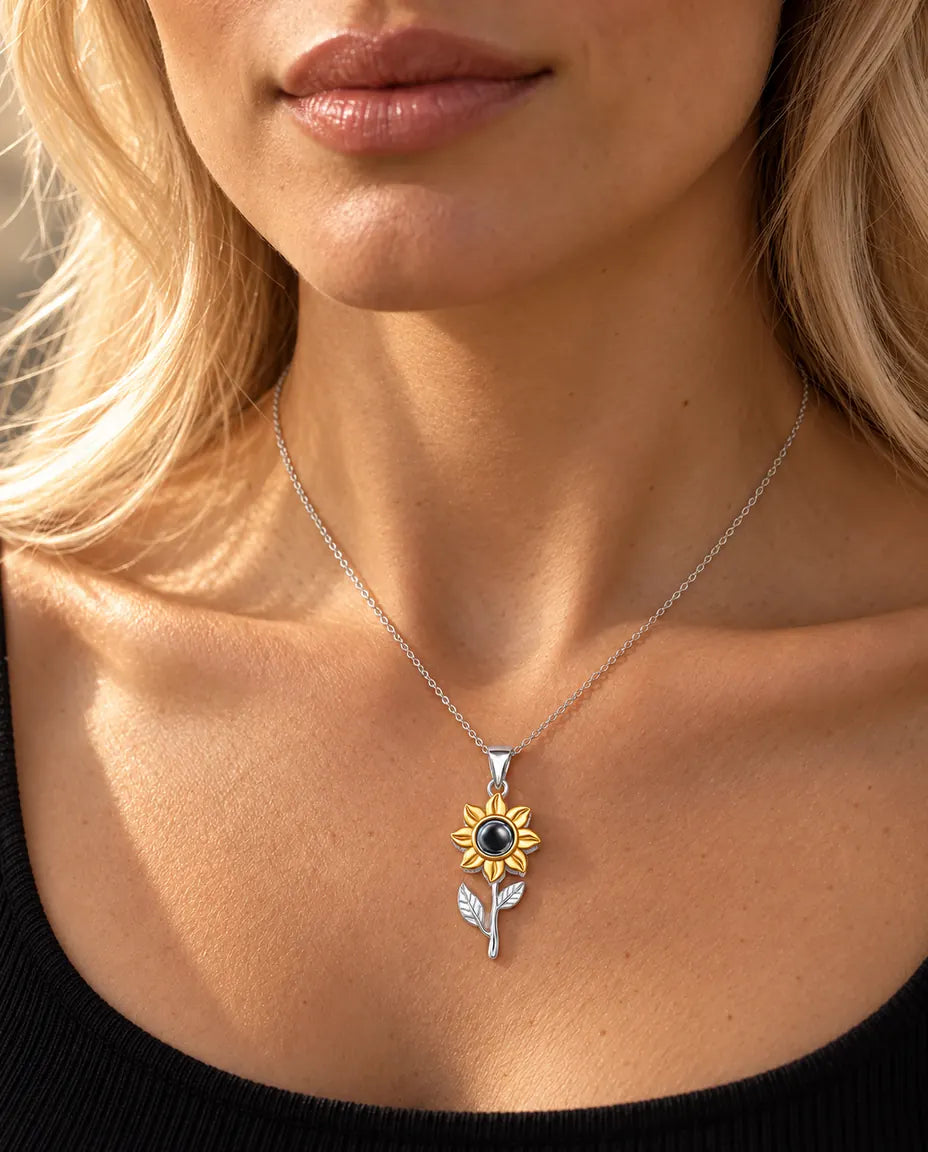 Mujer con un top negro que lleva el collar de plata con girasol sobre tallo y foto dentro