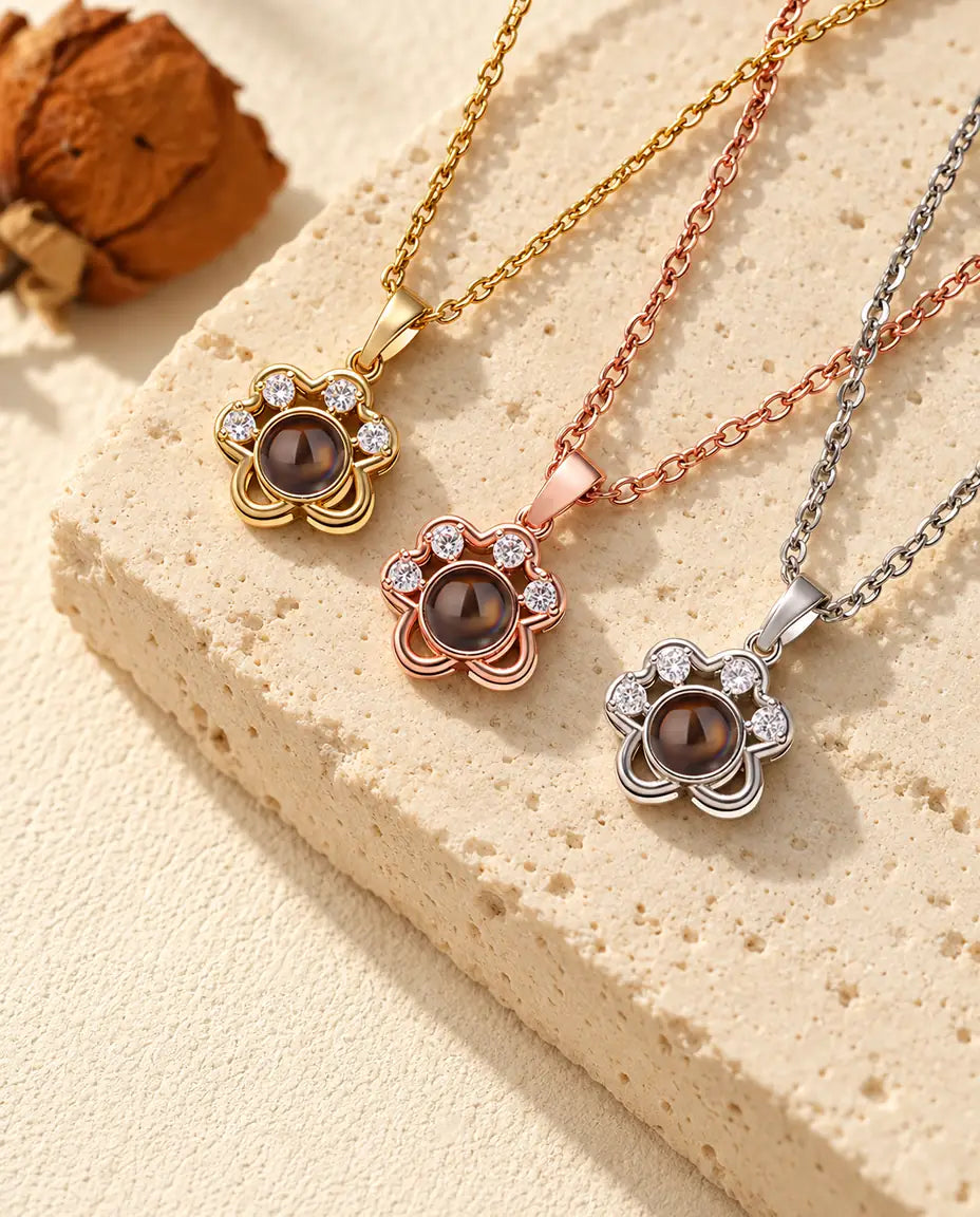 Collares de huella dorado, color oro rosa y plateado colocados en diagonal sobre travertino