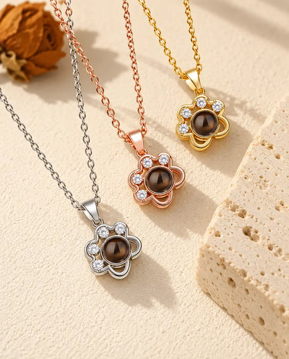 Los tres colores del collar de huella delicada con foto dentro, junto a un bloque de travertino