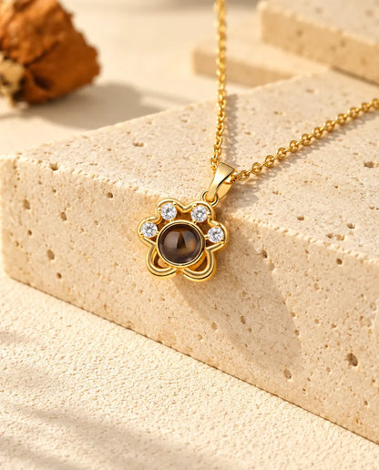 Collar de huella dorado con foto dentro, colgado sobre travertino