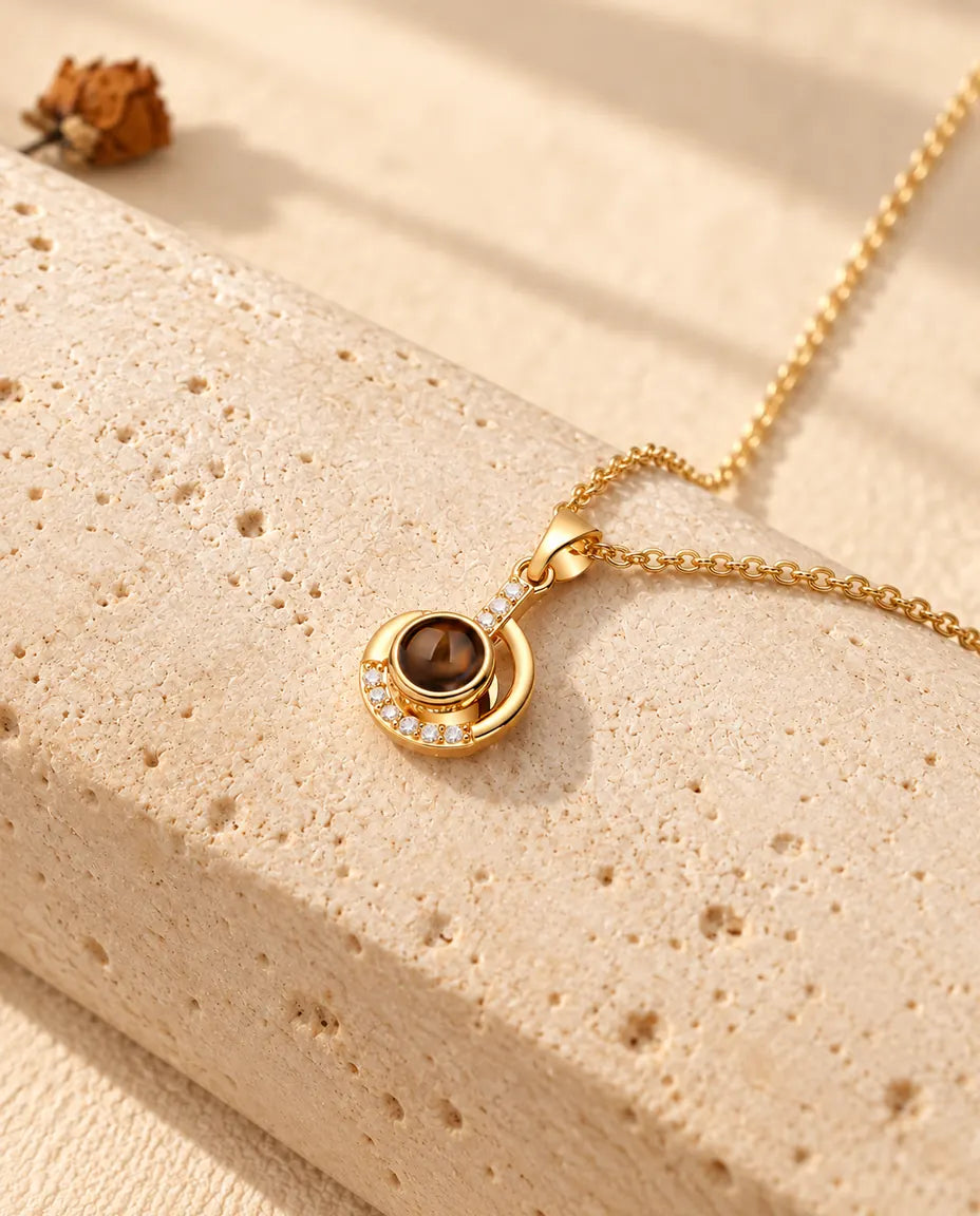 Collar de luna creciente dorado con foto dentro, colgado sobre travertino