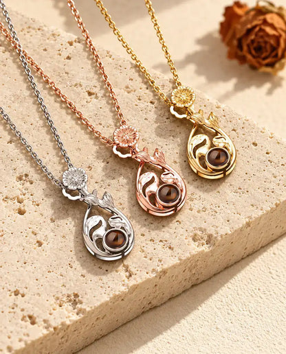 Tres collares de gota con flor uno junto a otro, con sus volutas de hojas