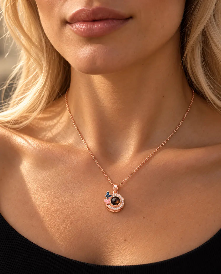 Mujer con un top negro de punto luciendo el collar color oro rosa de mariposas con foto dentro
