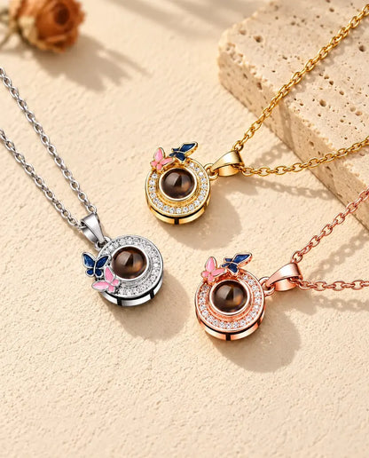 Collares de mariposas en dorado, plateado y color oro rosa, junto a una losa de travertino