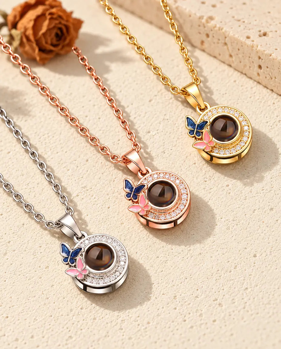 Los tres colores del collar de mariposas con foto dentro, en diagonal sobre yeso color crema