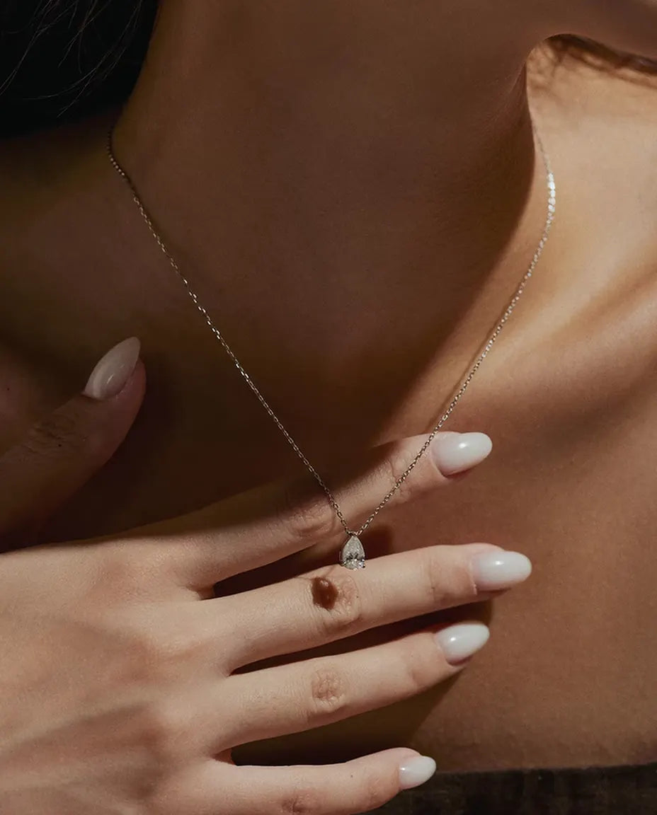 Collar de Moissanita Pera 1 ct en Plata 925 - llevado por una modelo con la mano en el cuello