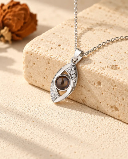 Collar con foto dentro de ojo turco plateado, tendido sobre un bloque de travertino