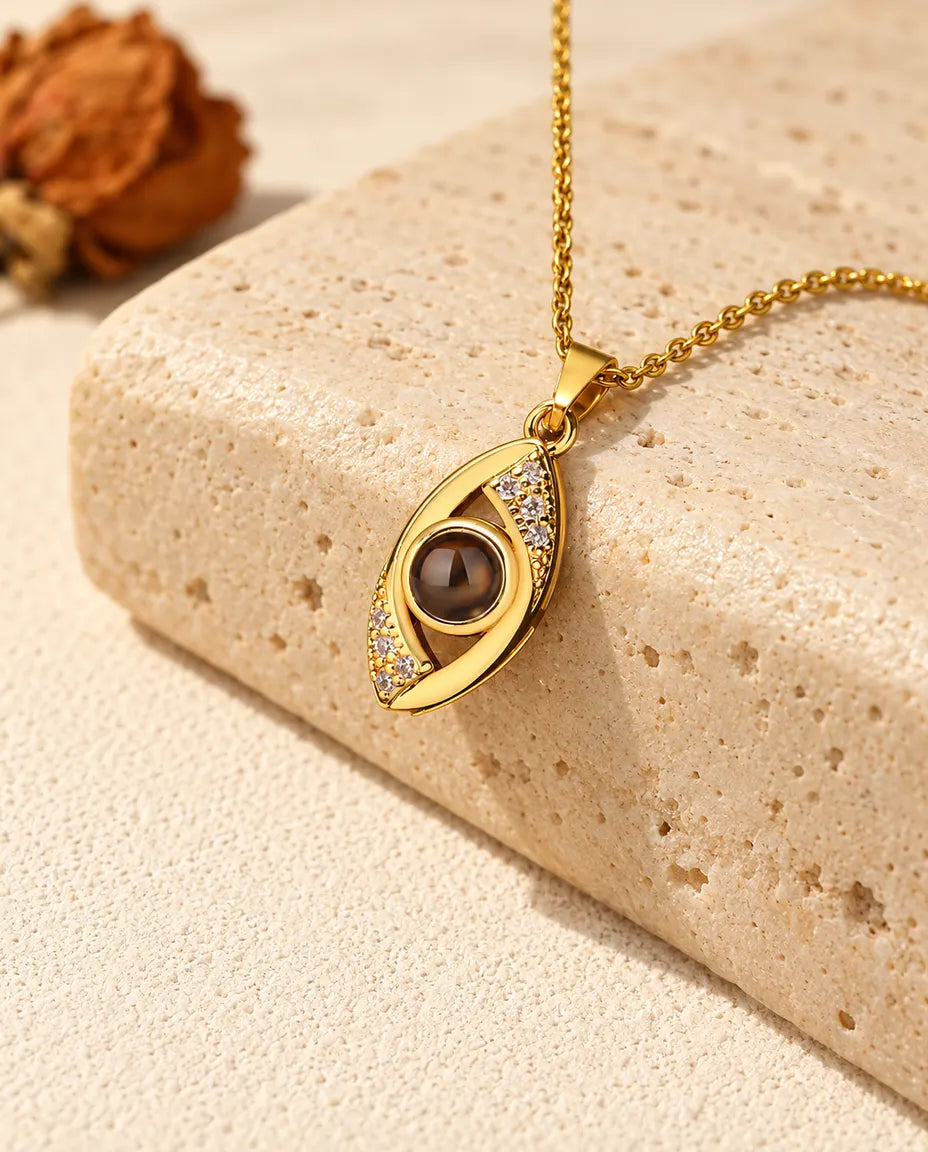 Collar de ojo turco dorado con foto dentro, colgado sobre travertino