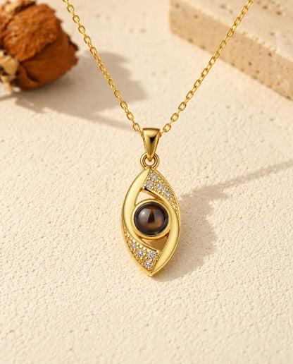 Vista frontal del colgante dorado de ojo de almendra, con la bola de proyección como iris
