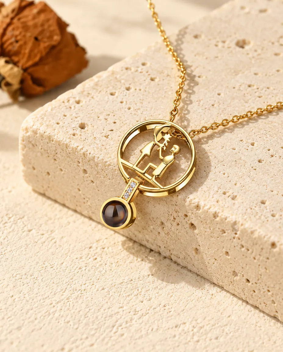 Collar con foto dentro de pedida de mano dorado, con la pareja y él de rodillas, sobre travertino