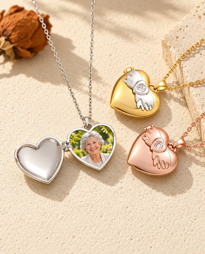 Relicario plateado con alas de ángel abierto con el retrato de una abuela, junto a dos cerrados en dorado y color oro rosa