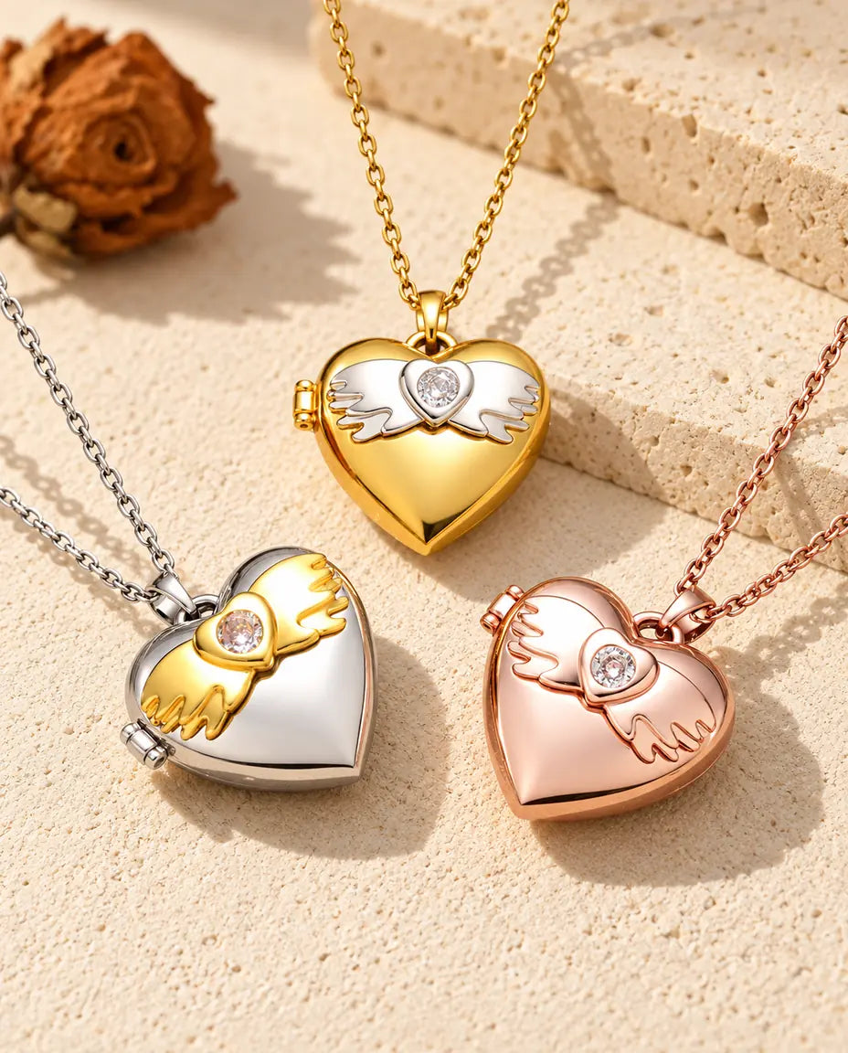 Los tres colores del collar relicario de corazón con alas de ángel, colocados juntos sobre yeso