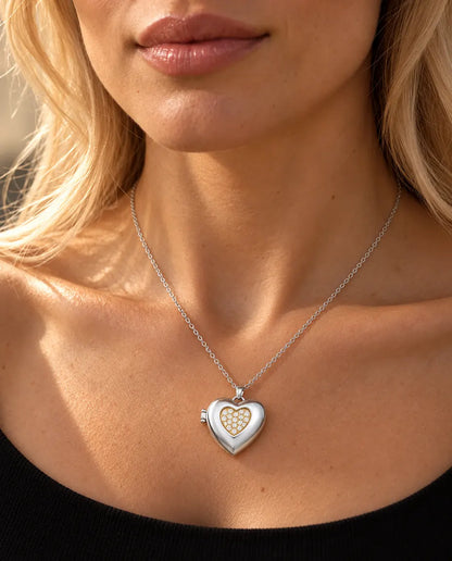 Mujer con un top negro de punto que lleva el collar relicario de corazón plateado con centro de circonitas