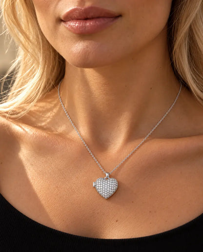 Mujer con un top negro de punto que lleva el collar relicario de corazón plateado cuajado de circonitas