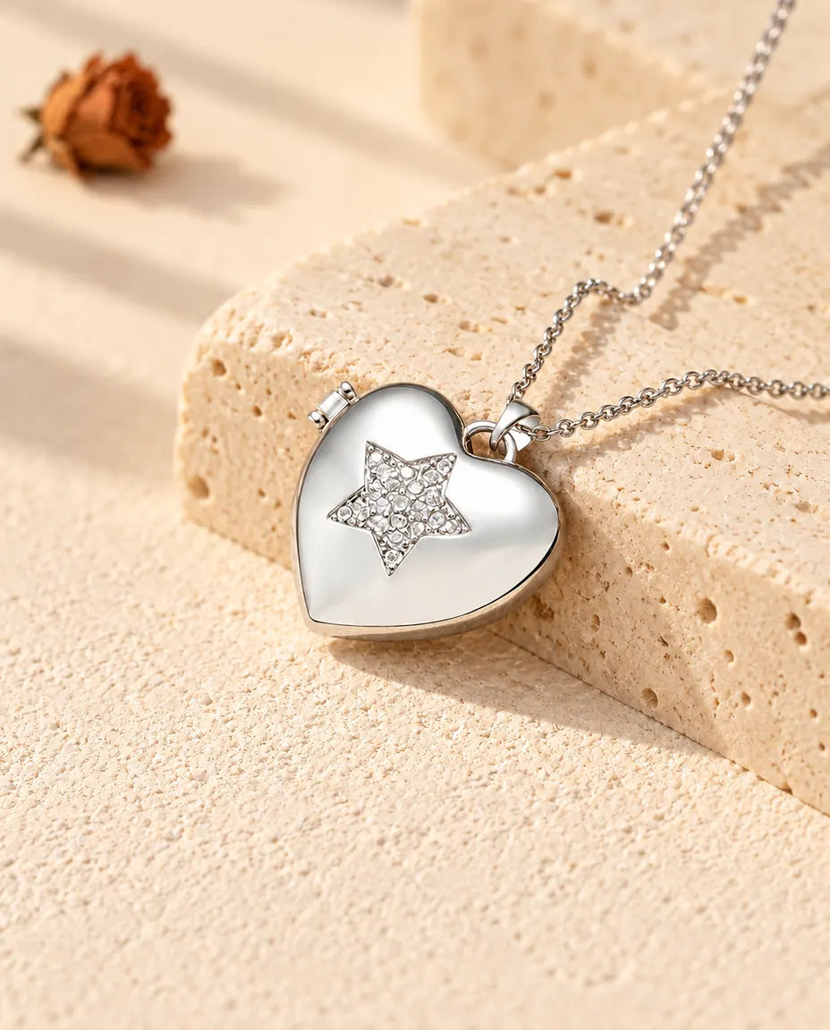 Relicario con foto de corazón plateado con una estrella cuajada de circonitas, apoyado en un bloque de travertino
