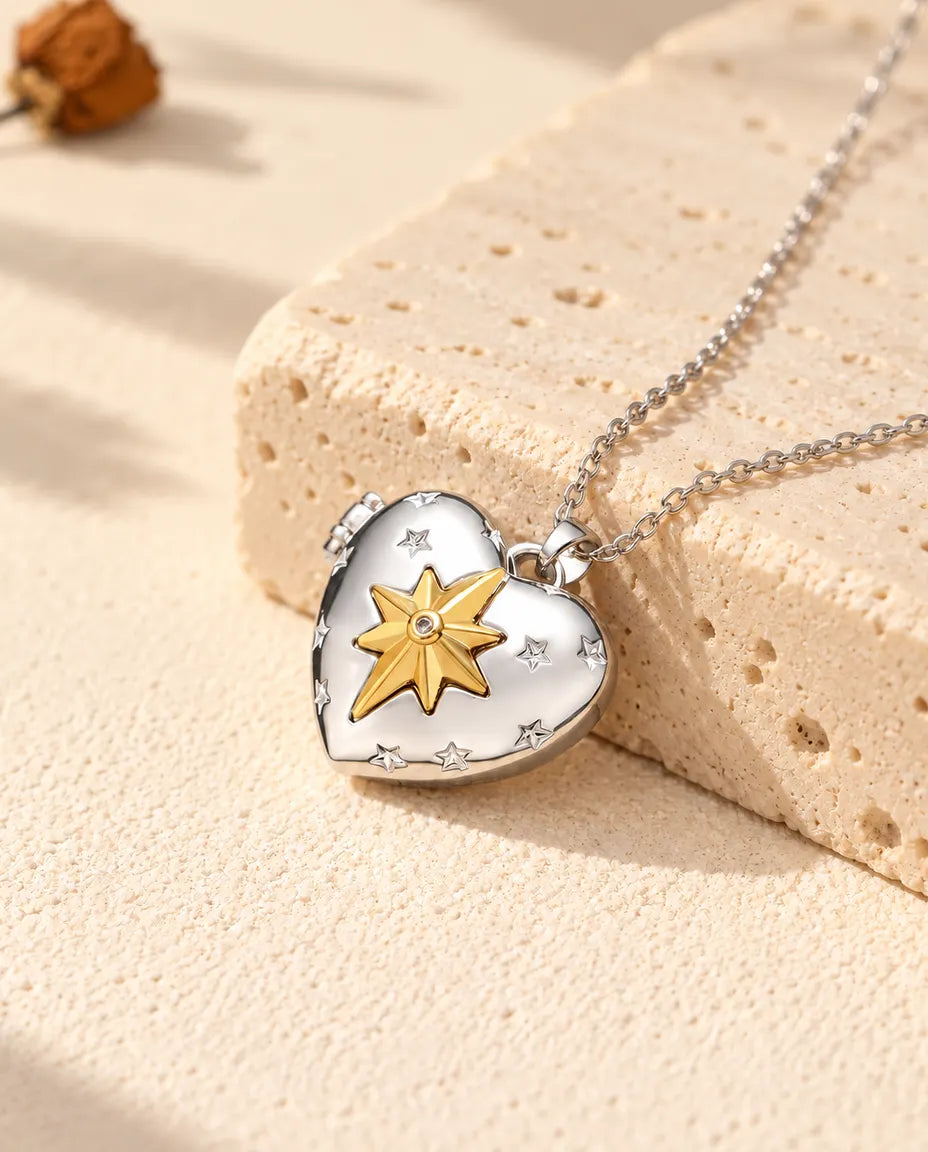 Relicario con foto de corazón plateado con una estrella polar dorada en relieve, apoyado en un bloque de travertino