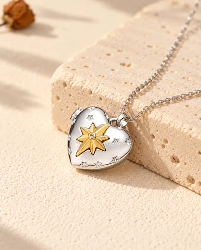Relicario con foto de corazón plateado con una estrella polar dorada en relieve, apoyado en un bloque de travertino