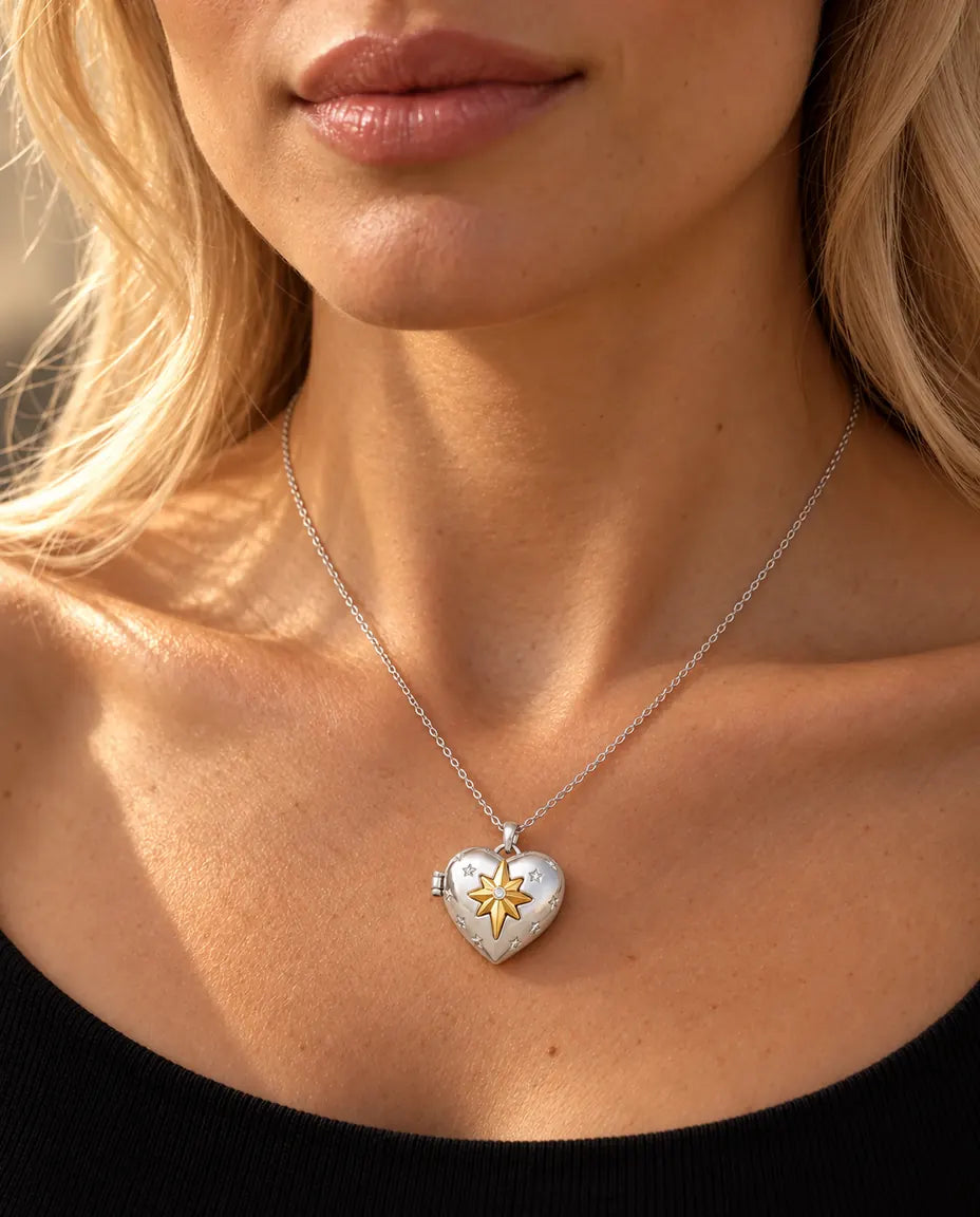 Mujer con un top negro de punto que lleva el collar relicario de corazón plateado con estrella polar