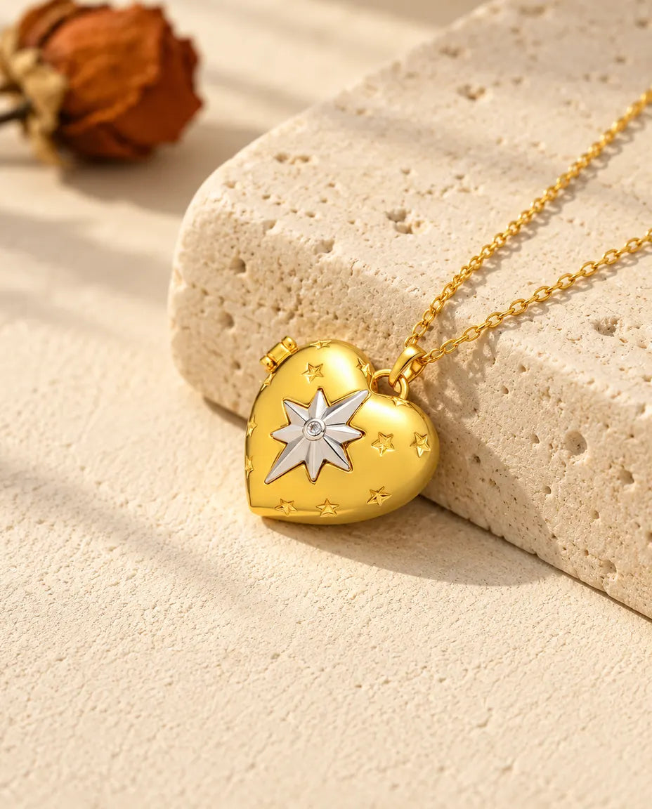 Collar relicario de corazón dorado con la estrella polar plateada, apoyado en un bloque de travertino