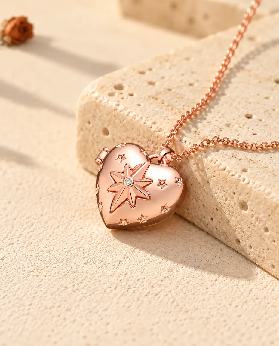 Collar relicario de corazón con estrella polar en color oro rosa sobre travertino, con luz cálida de sol