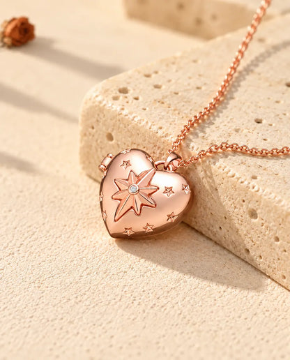 Collar relicario de corazón con estrella polar en color oro rosa sobre travertino, con luz cálida de sol