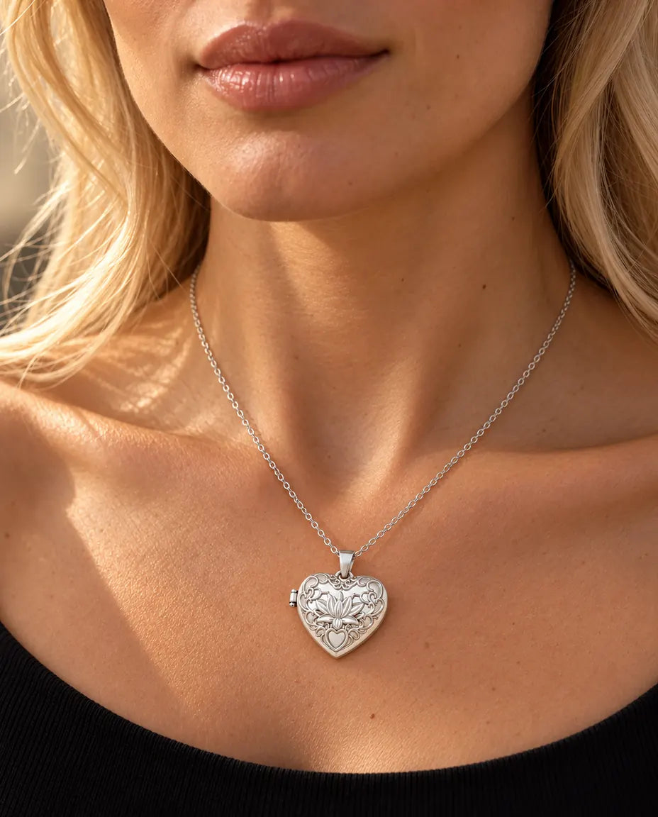 Mujer con jersey negro de punto que lleva el collar relicario de corazón plateado con flor de loto