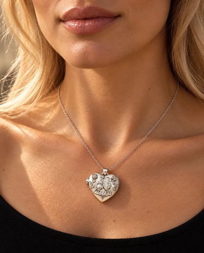 Mujer con jersey negro de punto que lleva el collar relicario de corazón plateado con las dos hermanas