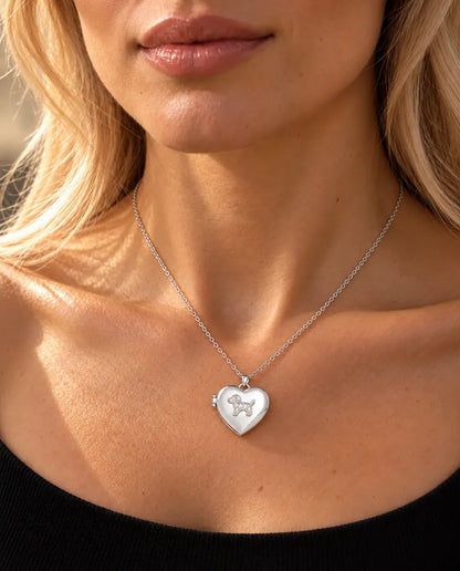 Mujer con un top negro de punto que lleva el collar relicario de corazón plateado con perrito