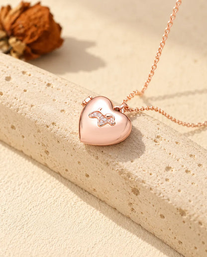Collar relicario de corazón con perrito en color oro rosa sobre travertino, con luz cálida de sol