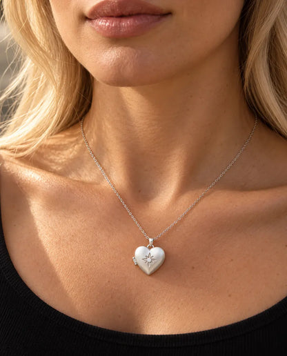 Mujer con un top negro de punto que lleva el collar relicario de corazón plateado satinado con flor