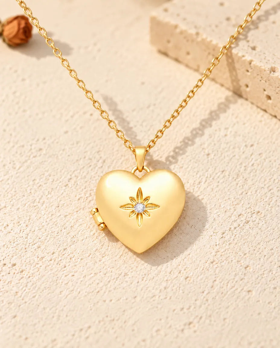Vista frontal del relicario de corazón dorado satinado con la flor central y la bisagra lateral