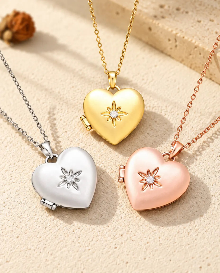 Los tres colores del collar relicario de corazón satinado con flor, colocados juntos sobre yeso