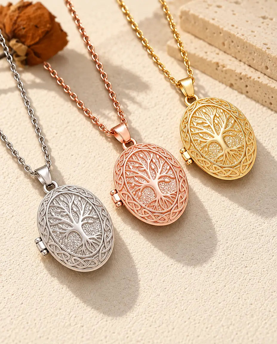 Tres relicarios con árbol de la vida, plateado, color oro rosa y dorado, colocados en diagonal sobre yeso crema