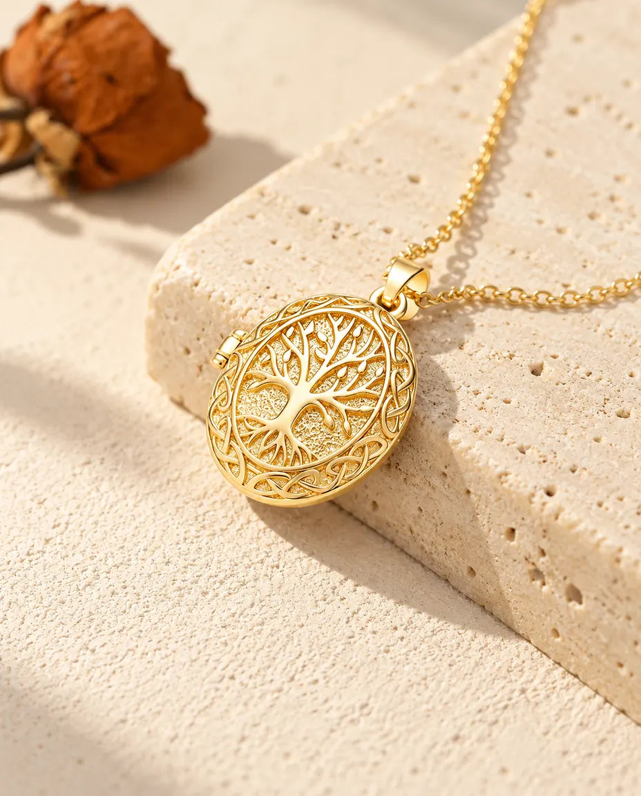 Collar relicario ovalado dorado con árbol de la vida colgado sobre el borde de un bloque de travertino